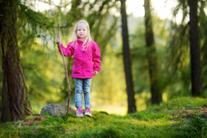 Little girl in a pink jacket on a forest hike on beautiful autumn day